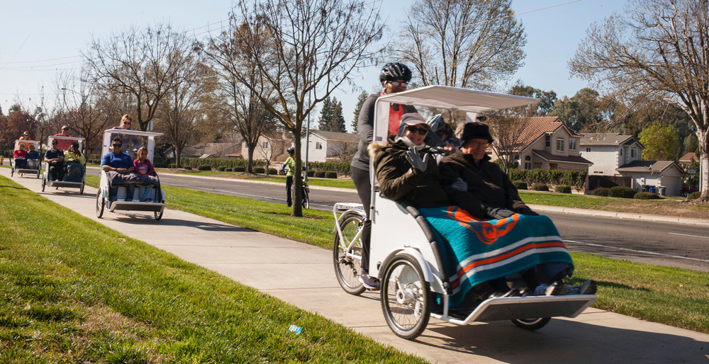 The white rickshaws caravan down R Street in Merced