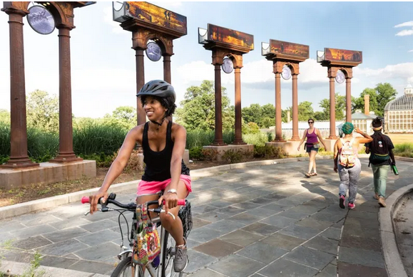 a woman rides a bike along a promenade