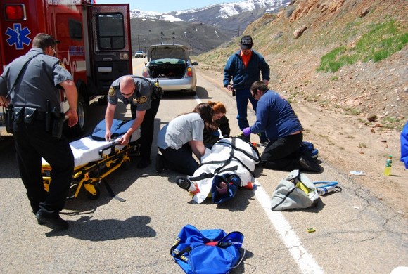 EMTs on the side of a road work to put traffic crash victim on a gurney