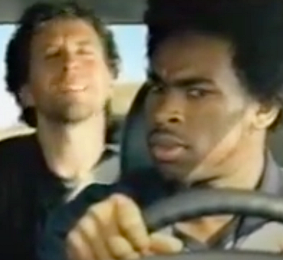 White passenger eyes closed; black driver looks quizzical